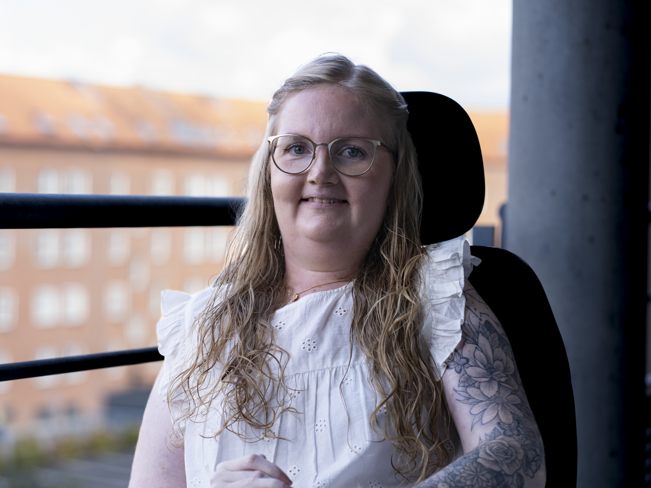 Julie Elmquist sidder i sin kørestol med en by i baggrunden